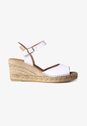 Sandalias de cuña de cuero blanca con tiras en el tobillo, tacón envuelto en yute, punta abierta y detalles de costura en los lados.
