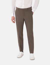 Bruine broek met een gestructureerde afwerking, smal toelopende pasvorm en ceintuurlussen, gecombineerd met witte sneakers en een overhemd met knopen.