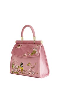 Bolso de mano de terciopelo rosa con forma estructurada, que presenta bordados de flores y pájaros, herrajes en tono dorado y un asa en la parte superior.