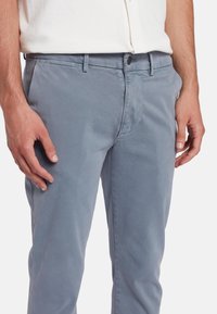 Lichtblauwe, slim-fit broek gemaakt van katoen; beschikt over een knoopsluiting en discrete zakken; gladde textuur met een casual ontwerp.