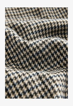 Strukturierter Stoff mit einem Hahnentrittmuster in Schwarz, Beige und Weiß, mit weichen, leicht flauschigen Fasern und einem drapierten Aussehen.