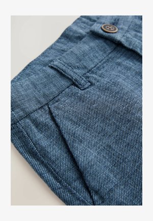 Tessuto in denim blu, con chiusura a bottone e dettagli cuciti. La texture presenta un motivo intrecciato e una finitura liscia.