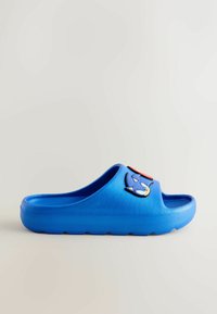 Blue slide sandal with thick sole featuring Sonic the Hedgehog character face on the strap, displayed against a plain white background.