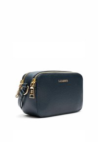 Piccola borsa rettangolare in pelle blu navy con texture a granuli, cerniera e accessori dorati, e logo in evidenza sul fronte. Tracolla regolabile.