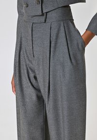 Grijze herringbone-patroon broeken met plooien, gemaakt van gestructureerde stof. Kenmerken zijn zijzakken en een hoge taille-ontwerp.