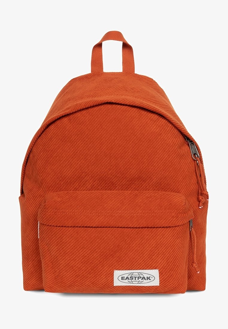 Sac à dos orange en velours côtelé avec une forme arrondie, une poignée supérieure, une poche avant zippée et le logo Eastpak sur une étiquette blanche. Surface texturée.