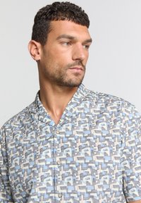 Korte mouwen overhemd met knopen in een geometrisch patroon van lichtblauw, grijs en crème op een gestructureerde stof met een Mandarin kraag.