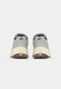 Gray suede and mesh sneakers with yellow accents, featuring a Vibram sole and reinforced heel, showcased from the rear.