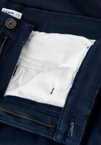 Navyblauwe broek met een rits- en knoopsluiting. De binnenzijde heeft een witte voering met een subtiele textuur en blauwe stikselaccenten. Maatlabel zichtbaar.