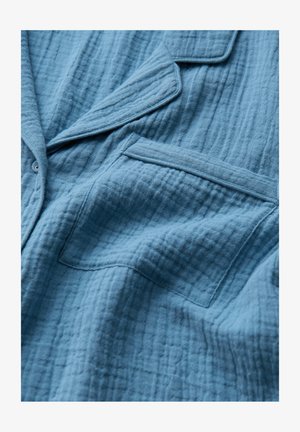 Blauer strukturierter Stoffjacke mit einem dezenten, gekräuselten Muster, ausgestattet mit einem Reverskragen und einer einzelnen Brusttasche. Weiches Material.