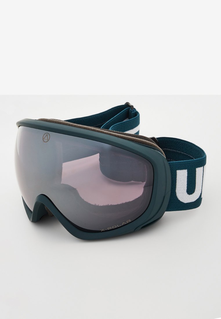 Skibril met getinte gebogen lens, donkergroene frame en verstelbare marineblauwe band met gedurfde witte letters op een neutrale achtergrond.