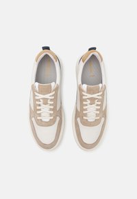 Λευκά δερμάτινα αθλητικά παπούτσια με καφέ σουέντ λεπτομέρειες και μπεζ επενδύσεις. Περιλαμβάνουν επίπεδες κορδόνες, κεφαλή υποδημάτων με μαξιλάρι και υφασμένη σόλα.