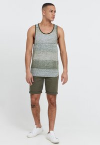 Débardeur à rayures grises et vertes, associé à un short olive et des baskets blanches. Le débardeur présente un col rond et un ourlet roulé ; le short est de longueur genou.