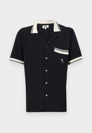 Černá košile s krátkým rukávem, bílým límečkem a kapsičkou s lemováním. Texturovaná látka s výšivkou ve tvaru srdce na kapse. Zapínání na knoflíky vpředu.