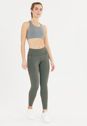 Grå sportbh och olivgröna högmidjade leggings, båda tillverkade av ett smidigt, stretchigt material. Funktioner inkluderar en åtsittande design och sidofickor.