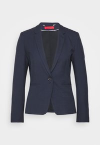 Blazer bleu marine cintré avec revers à encoches, fermeture par un seul bouton et deux poches avant. Confectionné en tissu texturé, intérieur non doublé.