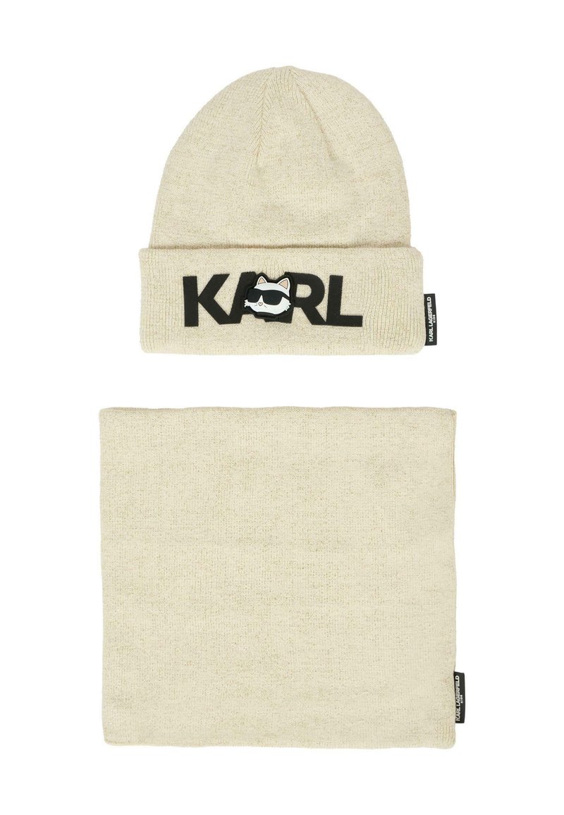Gorro de punto beige con "KARL" en letras negras y un logotipo de cara de dibujos animados; incluye un calentador de cuello beige a juego. Ambos tienen una textura suave.