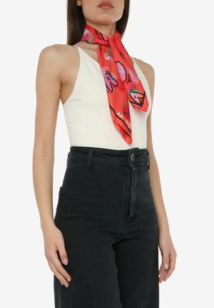 Foulard di seta di un brillante rosso con motivi astratti di smiley e geometrici. Legato elegantemente attorno al collo. Texture liscia, colori vivaci.