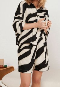 Zwarte en crèmekleurige zebra print shirt en short set van lichtgewicht stof met een relaxte pasvorm, voorzien van oversized mouwen en een elastische tailleband.