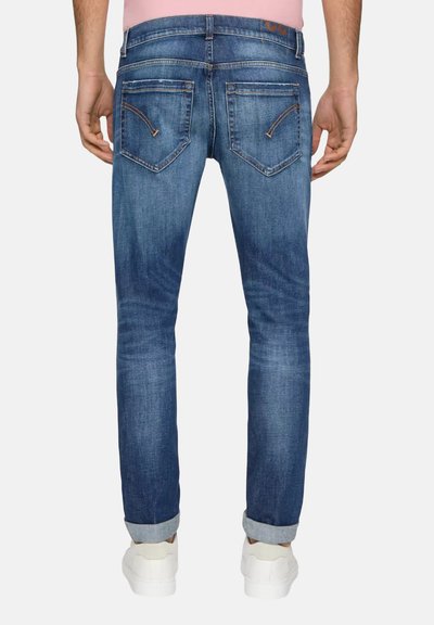 Jeans in denim blu con vestibilità comoda, dotati di due tasche posteriori, orli arrotolati e dettagli di cucitura arancione lungo le cuciture.