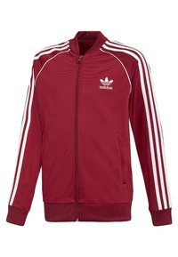 Veste zippée en polyester rouge avec des rayures blanches le long des épaules et des bras. Dispose du logo Adidas sur la partie gauche de la poitrine et de poches latérales.