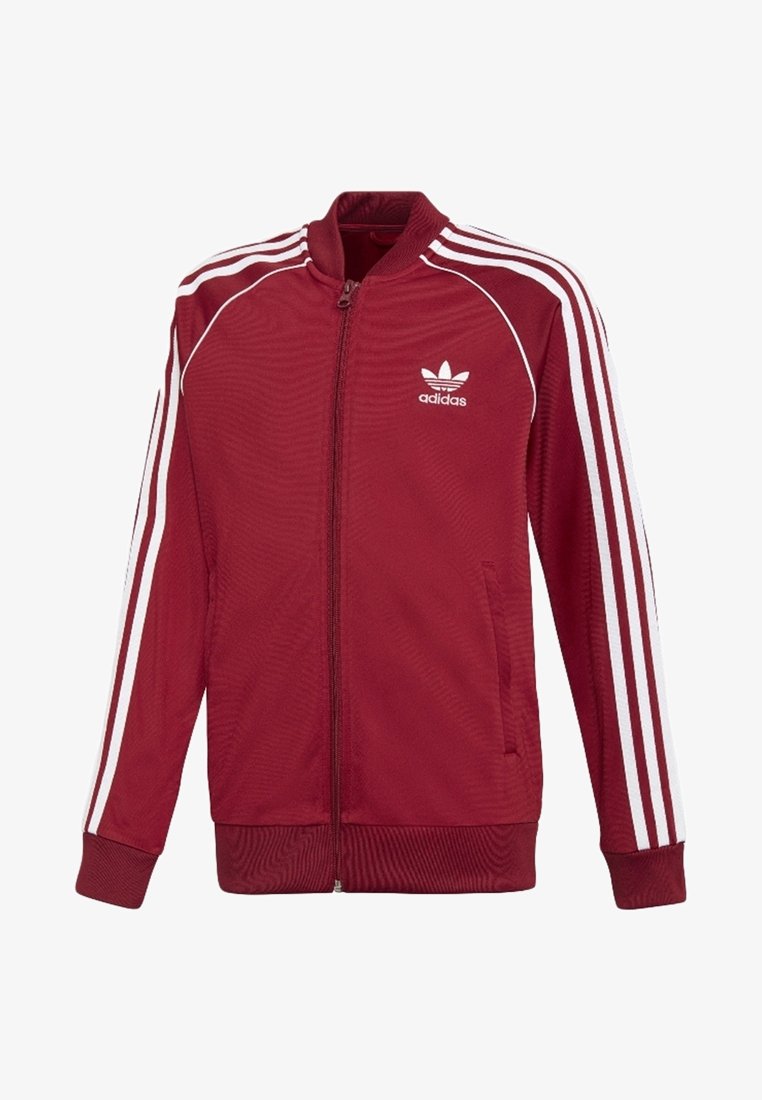 Veste zippée en polyester rouge avec des rayures blanches le long des épaules et des bras. Dispose du logo Adidas sur la partie gauche de la poitrine et de poches latérales.
