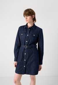 Dark denim shirt dress with a collared neckline, long sleeves, front button closure, two chest pockets, and a belted waist.