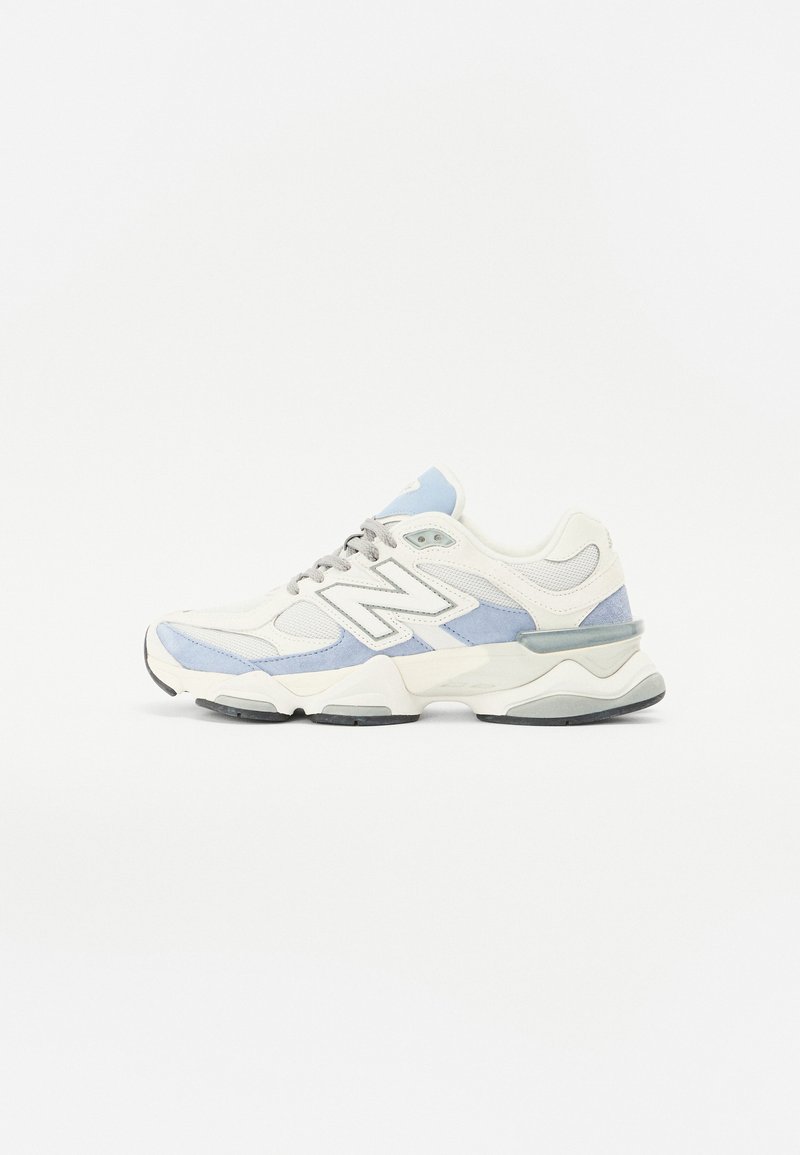 White sneaker with light blue and gray accents. Made of mesh and suede, featuring a thick sole and prominent logo on the side.