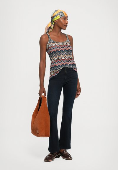 Multicolored zigzag tank top, dark blue flared jeans, brown suede handbag, and shiny dark shoes, with a patterned scarf tied around the head.
