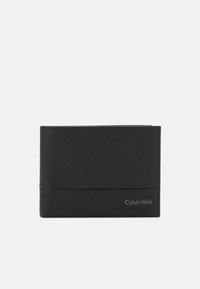 Portafoglio in pelle nera con una sezione superiore testurizzata, sezione inferiore liscia e un logo "Calvin Klein" in argento in basso a destra.
