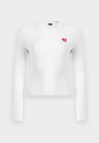 Haut blanc à manches longues en tissu côtelé avec un petit logo cœur rouge sur le côté gauche de la poitrine. Le tissu a une texture lisse et une coupe ajustée.