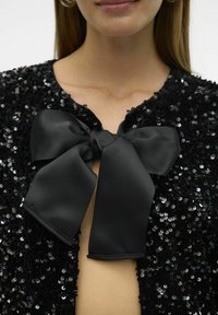 Cardigan de lentejuelas negras con escote redondo y cierre de lazo de satén negro en el frente, que presenta una superficie texturizada y brillante.