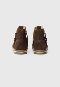 Botas de tobillo de ante marrón con punta redonda, cremalleras laterales y una suela de goma texturizada que presenta dos franjas horizontales.