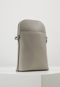 Liten upprätt grå lädercrossbodyväska med pebblad textur och silverfärgad dragkedjedetalj på vit yta.