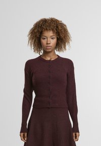 Cardigan en tricot bourgogne avec un col rond, des manches longues et des boutons noirs sur le devant. Tissu texturé avec une finition douce.