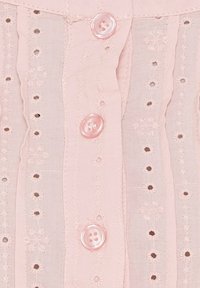 Lyserød bluse med broderede blomster mønstre, små udskæringer, og runde lyserøde knapper ned foran. Blødt, struktureret stof.