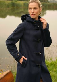 Cappotto duffle navy realizzato in lana testurizzata, con cappuccio, chiusure a nodo e tasche laterali con dettagli a bottone.