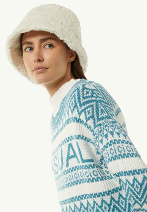 Cappello a secchiello bianco e soffice con una texture morbida. Maglione blu e bianco con un motivo geometrico e la scritta "CASUAL" sul petto.