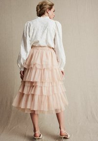 Hvid bluse med blomsterbroderi og pufærmer, parret med en lagdelt blush pink tylskørt. Skørtet har en elastisk talje og flæser.