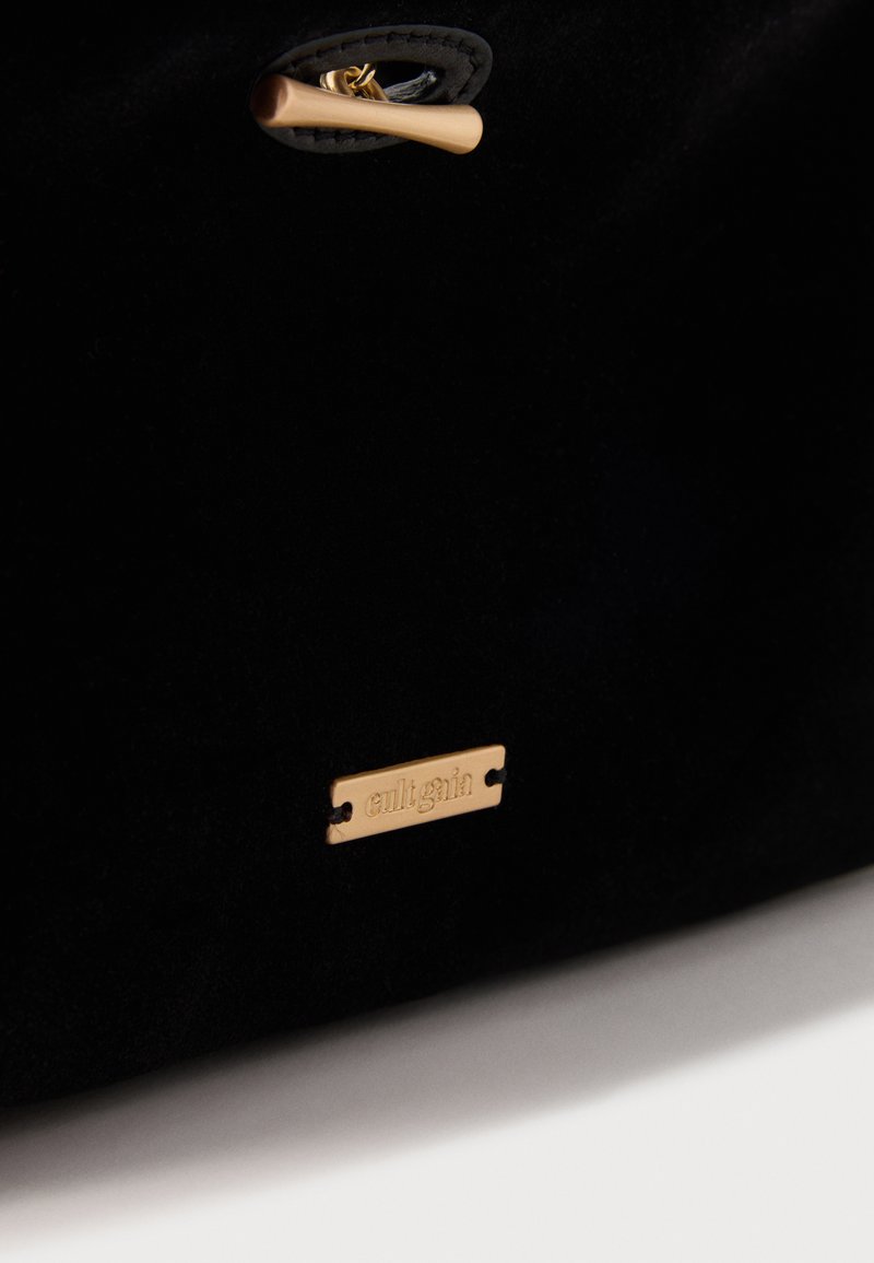 Borsa in velluto nero con piastra del logo in metallo dorato. Presenta una chiusura a scatto dorata e una texture levigata. Design elegante e moderno.