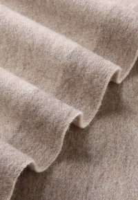 Beige felt fabric with fine texture, showing soft waves and light fibers. The surface is slightly fuzzy with a smooth appearance.