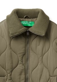 Olivově zelená prošívaná bunda s žebrovým límcem a zipovým zapínáním, se štítkem s nápisem "United Colors of Benetton."