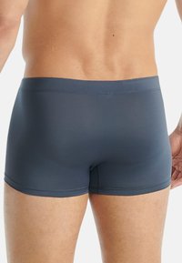 Marineblå badshorts med tight passform, tillverkade av slätt material. Har en midja och en minimalistisk design utan mönster eller logotyper.