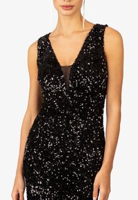 Schwarzes Paillettenkleid mit tiefem V-Ausschnitt und ärmellosem Design, mit einem transparenten Einsatz im Oberteil und strukturierten Verzierungen.
