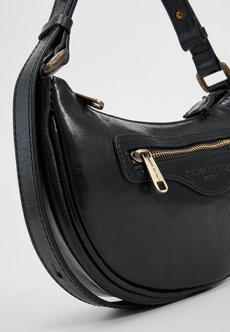 Czarna skórzana torba na ramię o zaokrąglonym kształcie. Posiada złoty zamek błyskawiczny i detale przeszycia. Regulowany pasek umożliwia różne sposoby noszenia.