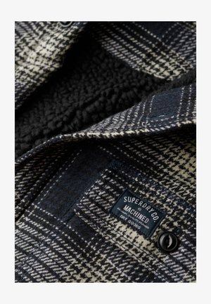 Checkered black and white flannel shirt with a soft, fuzzy interior, featuring a black button and a label reading "Superdry Co."