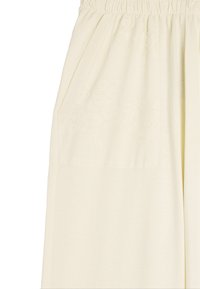 Beżowe spodnie o szerokich nogawkach z elastycznym paskiem i teksturowanym haftem kwiatowym na jednej kieszeni. Miękki, lekki materiał.