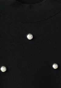 Maglione nero realizzato in tessuto a maglia testurizzata, con grandi bottoni argentati come dettagli, disposti in un motivo simmetrico sulla parte anteriore.