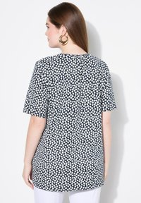 Top de manga corta azul marino con estampado floral blanco, que presenta un corte relajado y detalle de pliegue en la parte posterior. Tela suave y ligera.