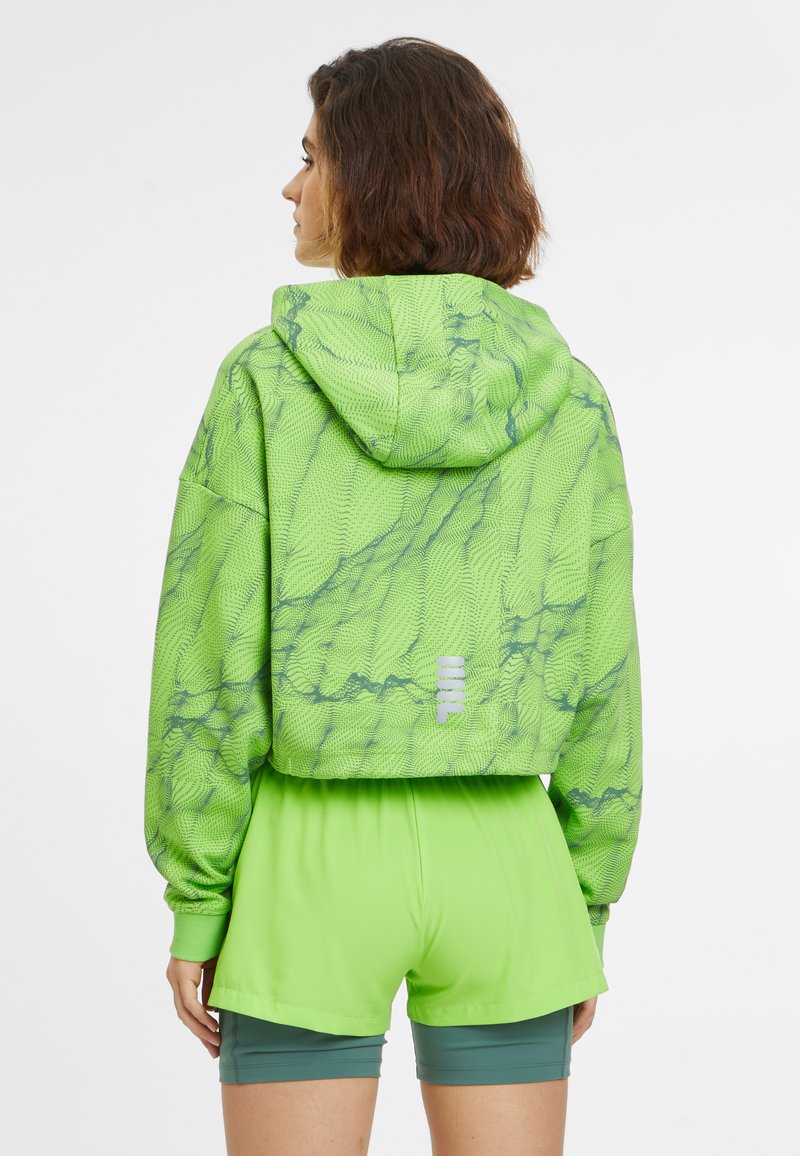 Chándal recortado con capucha de color verde brillante con un patrón texturizado, combinado con pantalones cortos verdes a juego. Presenta un detalle del logo visible en la parte posterior.